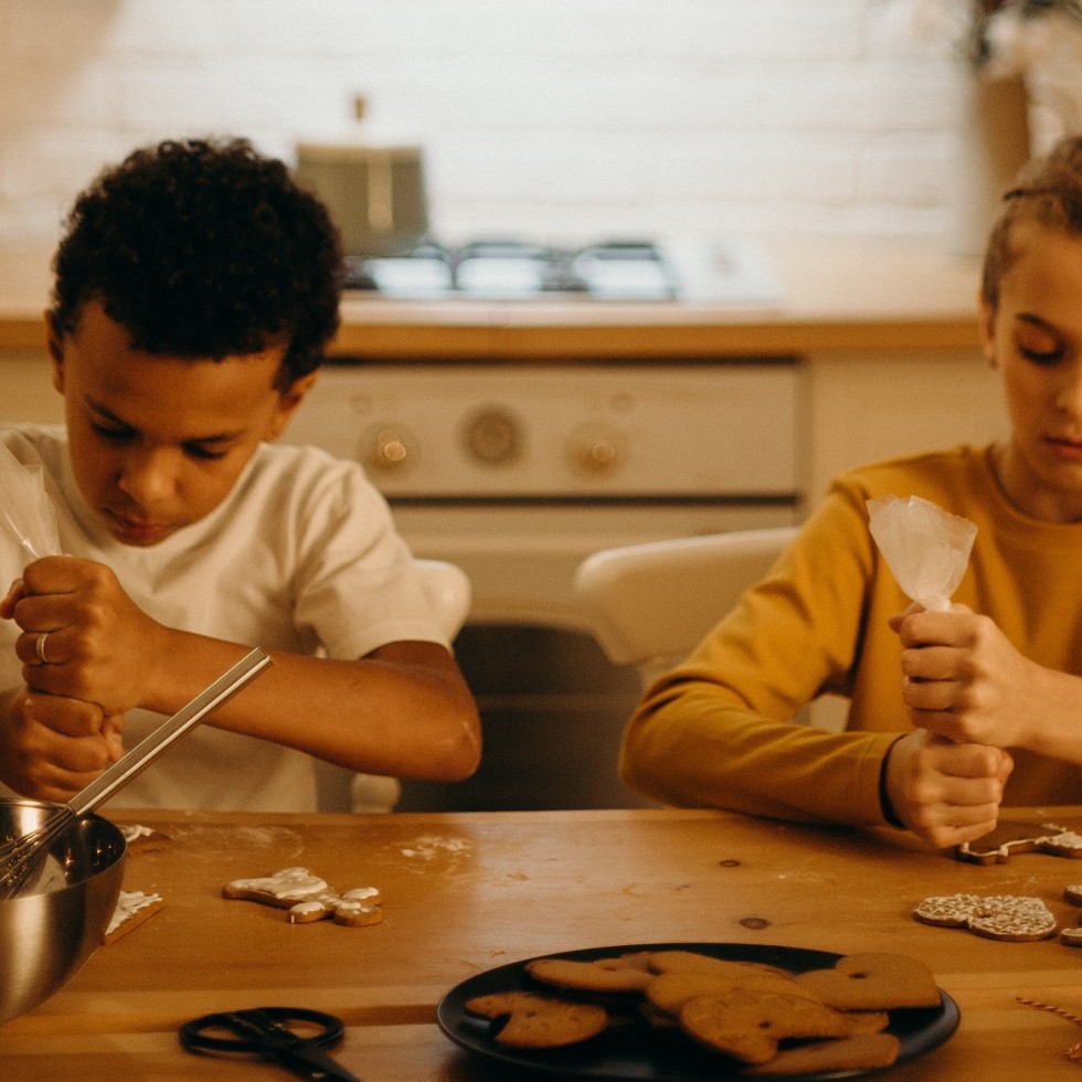 Kaksi nuorta lasta leipovat pipareita.