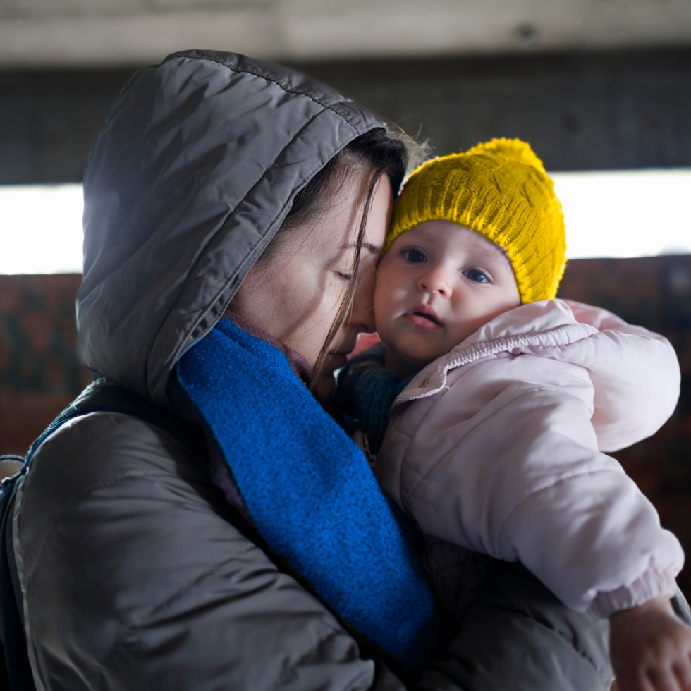 Äiti pitää lastaan sylissä pommisuojassa, Ukrainassa.